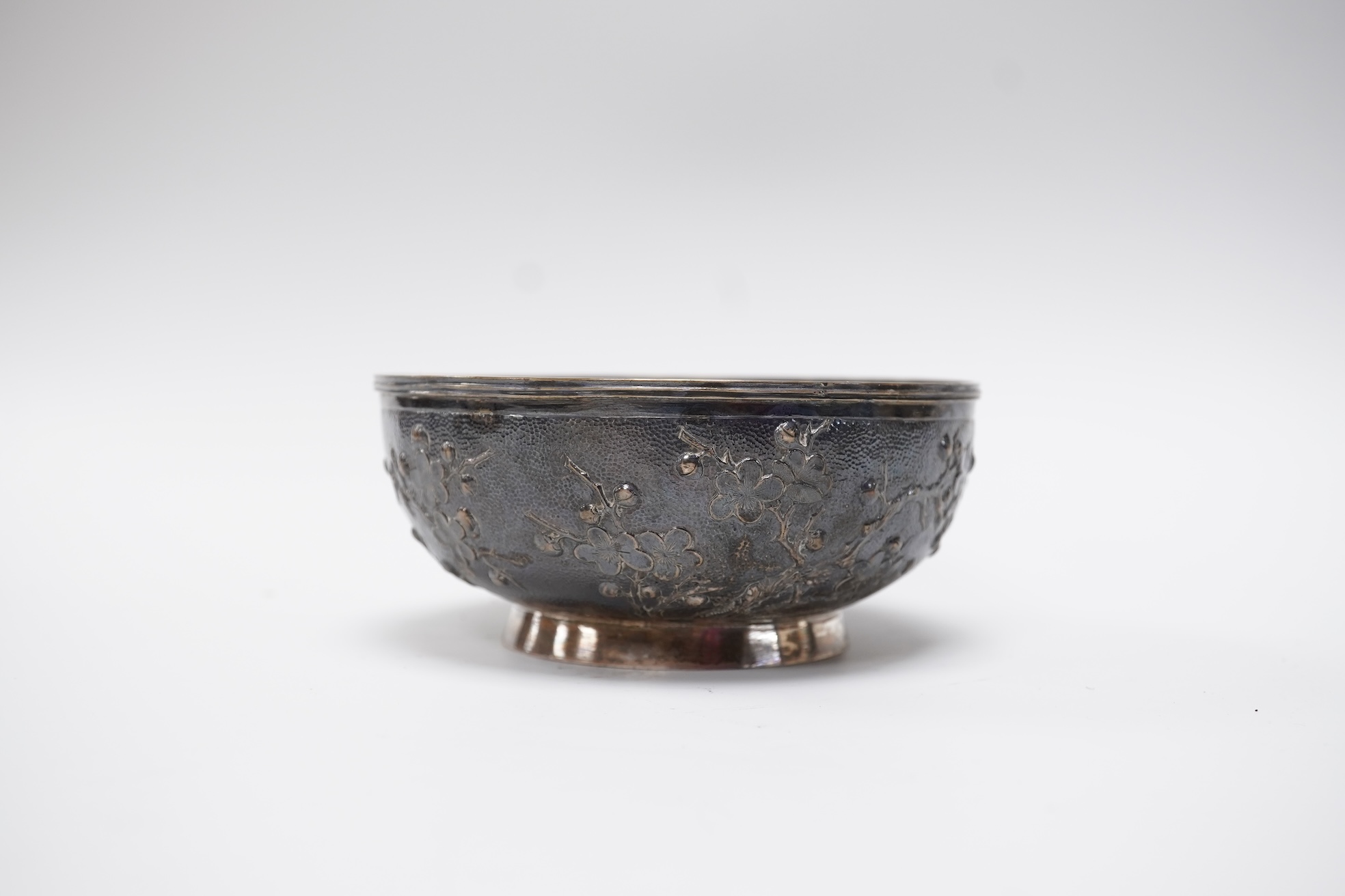 A late 19th/early 20th century Chinese Export white metal bowl, by Wang Hing, Hong Kong, embossed with blossoming prunus branches, diameter 10.6cm, 113 grams.